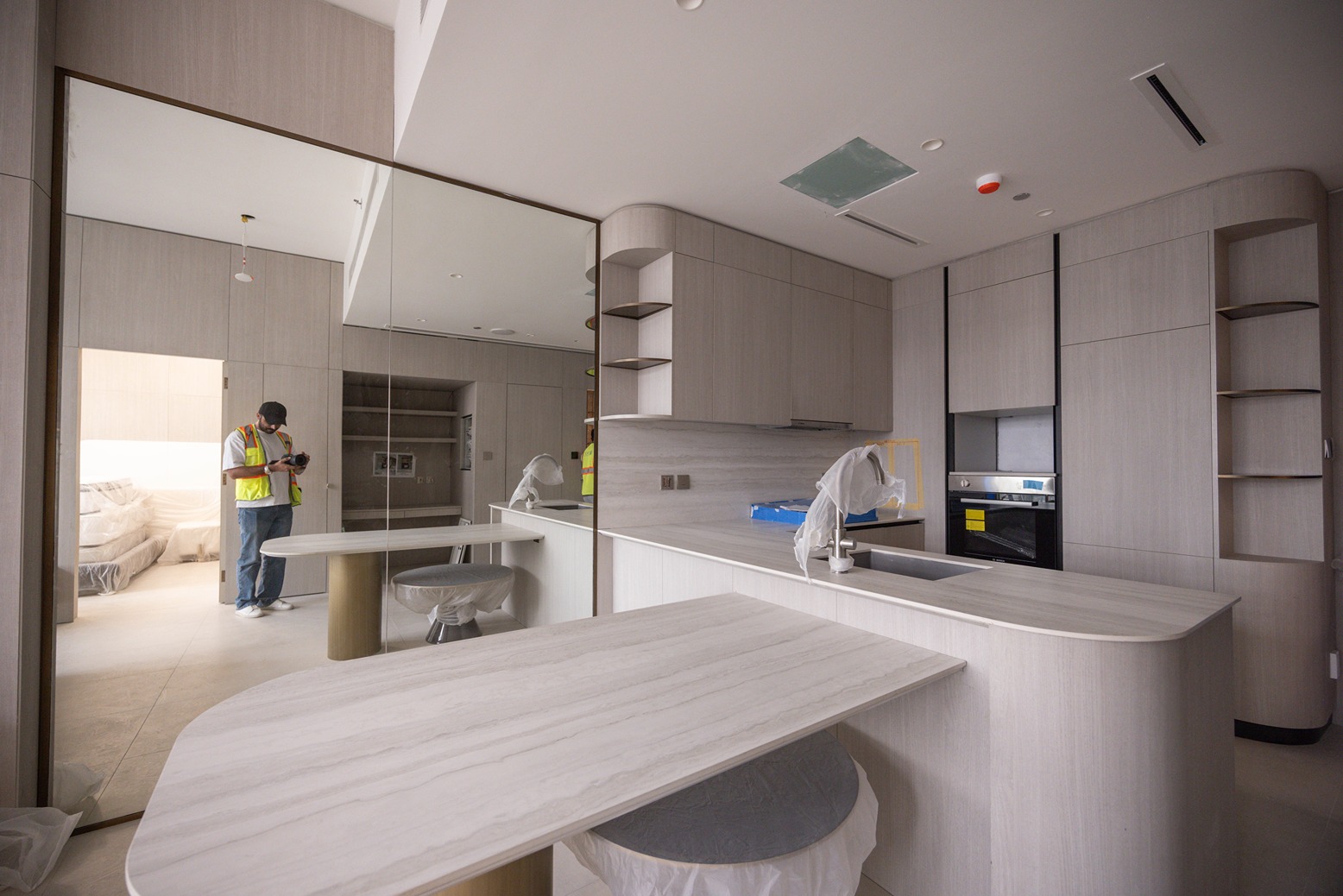 Pearl House By Imtiaz A modern kitchen with light cabinetry and a photographer in a safety vest capturing images of the space.